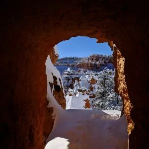 A natural sandstone window caves in with snow during the winter in Utah.