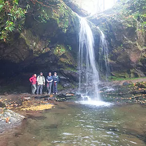 Four hikers next to a rushing waterfall in the Great Smoky Mountains