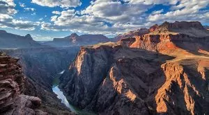Sun streaks through the clouds touch the vastness of the Grand Canyon.